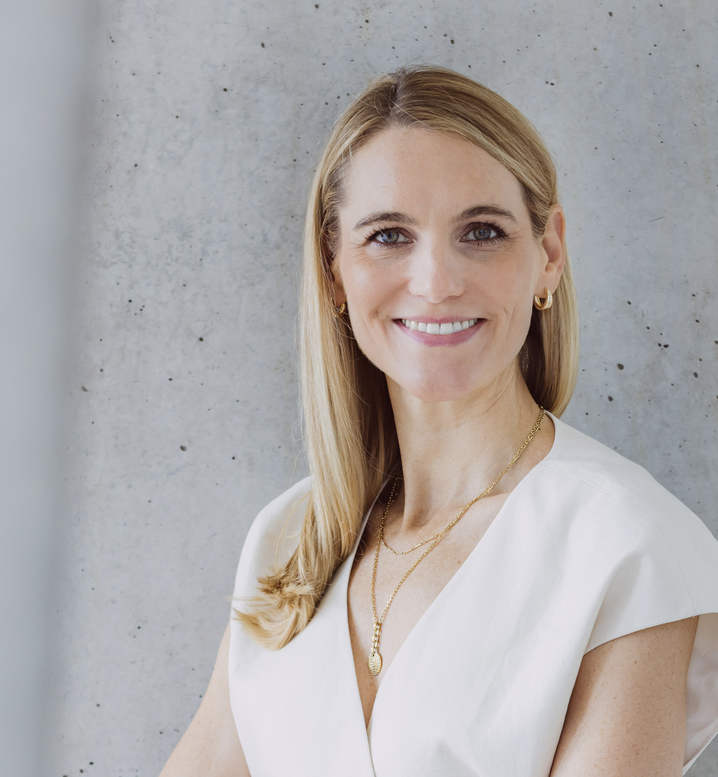 Dies ist Foto von Life, Business und Health Coach Dr. Kirsten Schlömer. Es ist ein Portrait. Sie trägt eine weiße Bluse mit V-Ausschnitt und eine Kette.